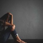 Girl holding her head while sitting on the floor