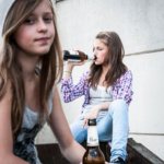 Две девочки сидят со спиртным, одна пьет с горла