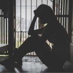 Грустная девушка сидит в темном углу